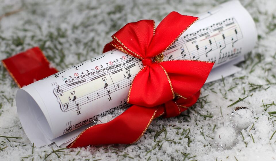 sheet music, red ribbon, music scroll, snowy background, winter music, holiday gift, christmas music, festive ribbon, music and snow, pine needles, seasonal decor, holiday wrapping, winter scene, elegant gift, red bow, music present, festive mood, snowy ground, christmas composition, classical music, music roll, holiday season, winter creativity, christmas spirit, festive decoration